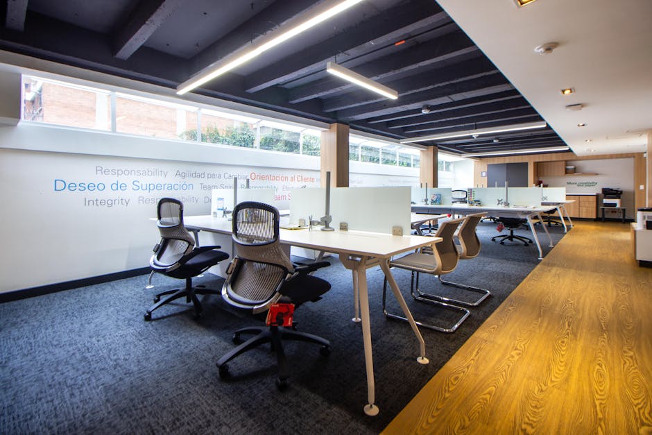 Dobro osvjetljeni moderni uredski prostor s ergonomskim stolicama i staklenim pregradama
